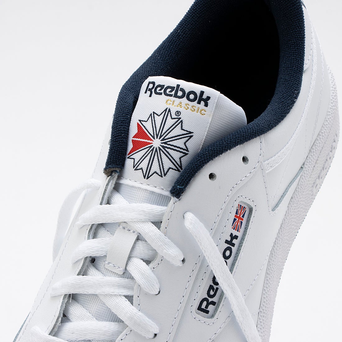 タンの拡大：CLASSICロゴとひも通し。写真：Reebok公式RE1759BU15178商品ページ